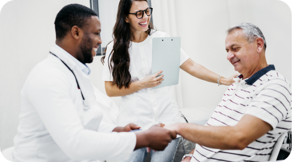 Médico y enfermera sonriendo y estrechando la mano de un paciente, simbolizando atención y cuidado.
