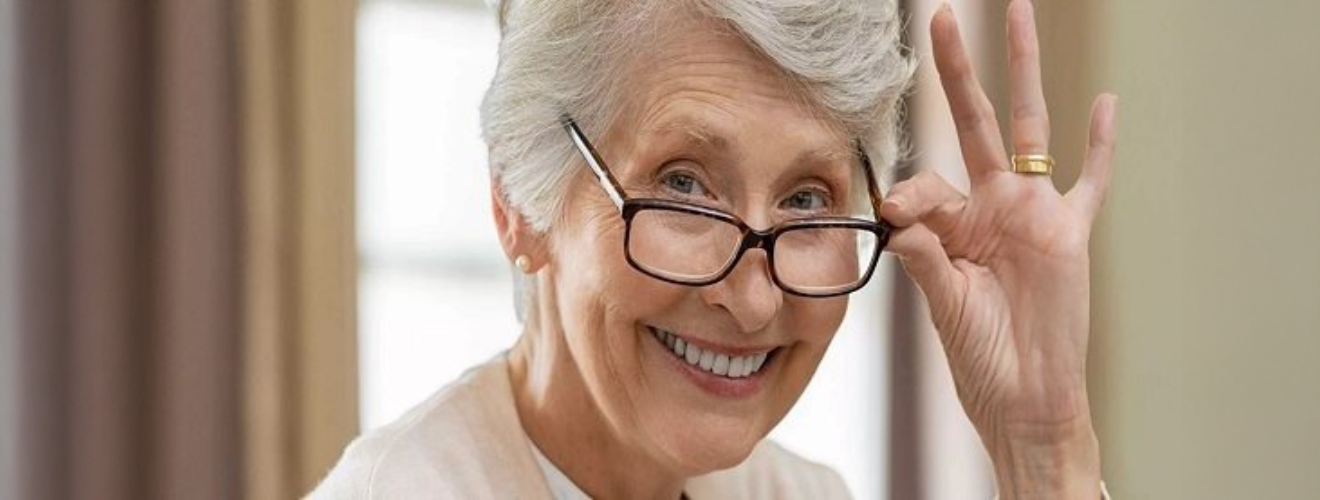 Ältere Patientin mit Brille lächelt in die Kamera und scheint wieder besser zu sehen