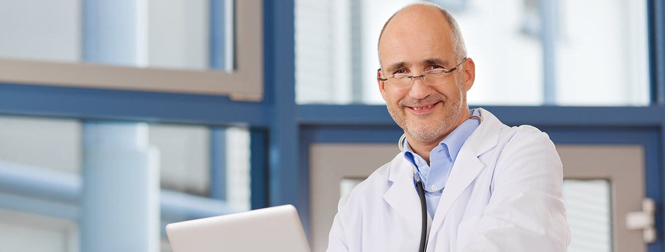 Doktor mit Laptop schaut in die Kamera