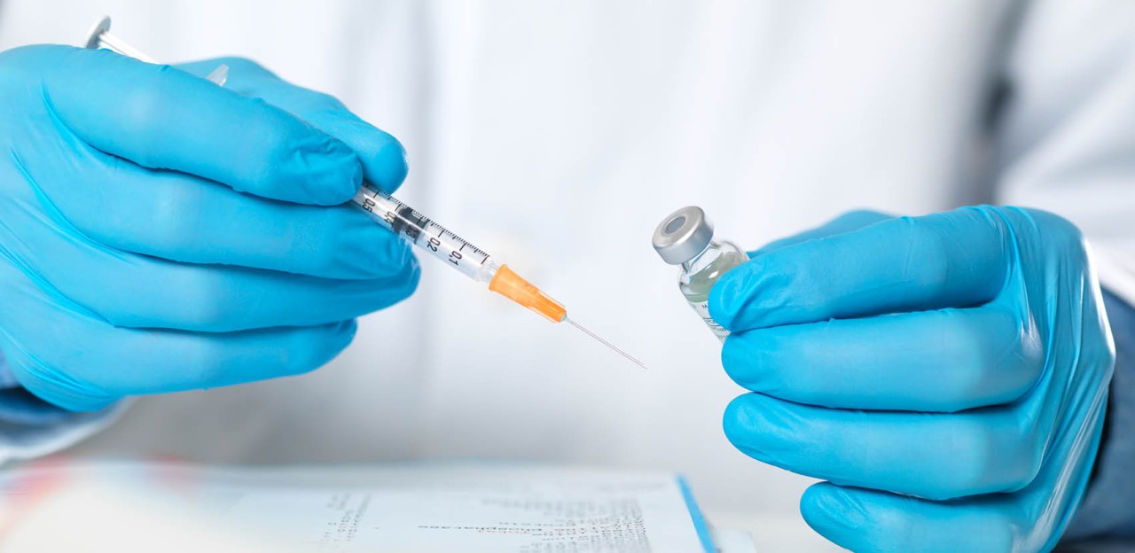 Image of a healthcare professional gloved hands holding a syringe and vial